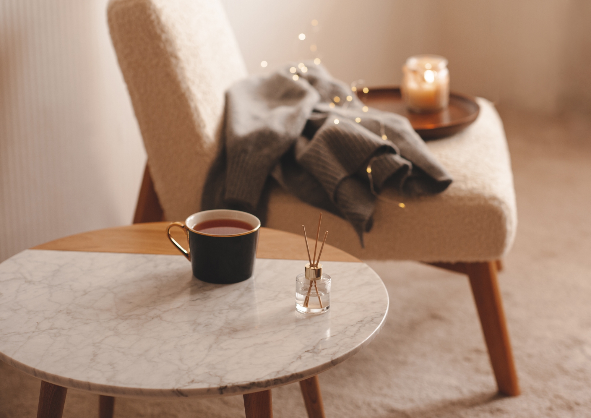 Angolo cozy con poltrona, coperta grigia e tazza fumante: rituali d’autunno